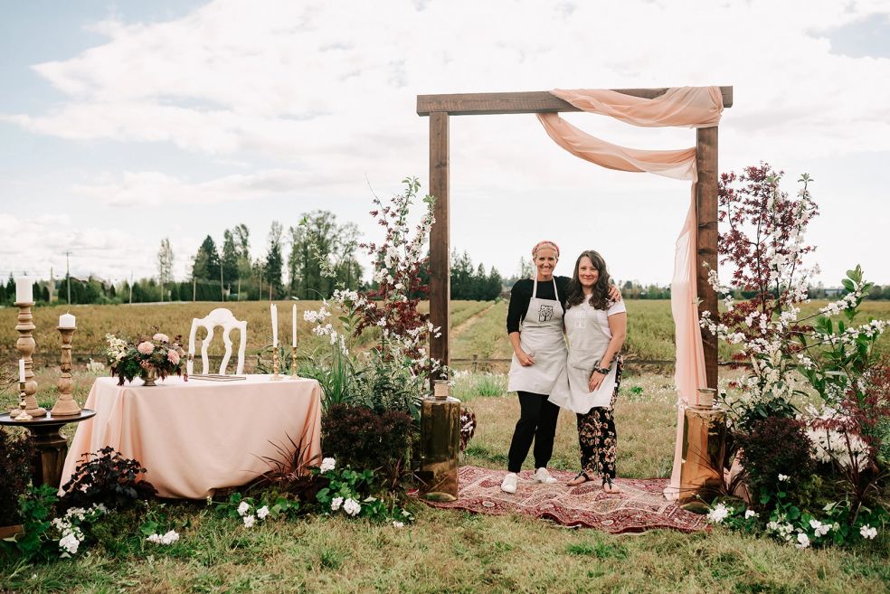 Andrea and Carmen of Rosewood Event Design standing in front of wedding florals and event decor at a Fraser Valley wedding